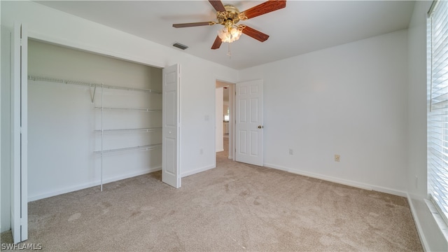 unfurnished bedroom with ceiling fan, a closet, and light carpet