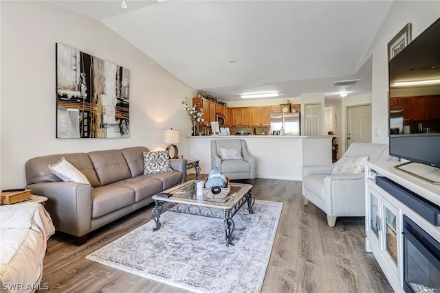 living room with vaulted ceiling and light hardwood / wood-style flooring