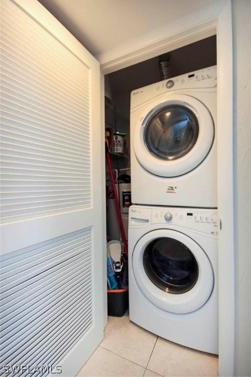 clothes washing area featuring stacked washer / dryer, laundry area, and light tile patterned floors