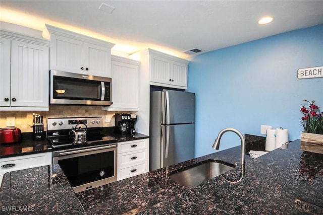 kitchen with appliances with stainless steel finishes, a sink, visible vents, and white cabinets