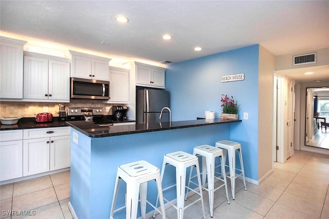 kitchen featuring stainless steel appliances, visible vents, a breakfast bar area, and light tile patterned floors