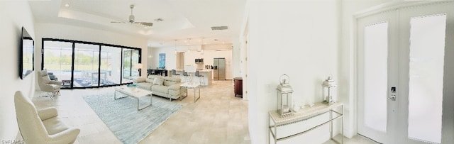 living room with ceiling fan and a raised ceiling