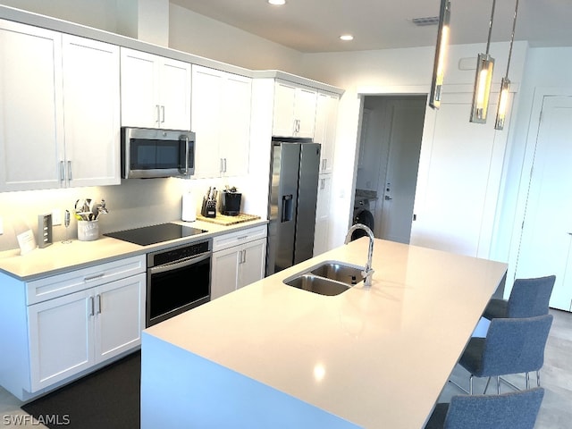 kitchen with stainless steel appliances, a center island with sink, and sink