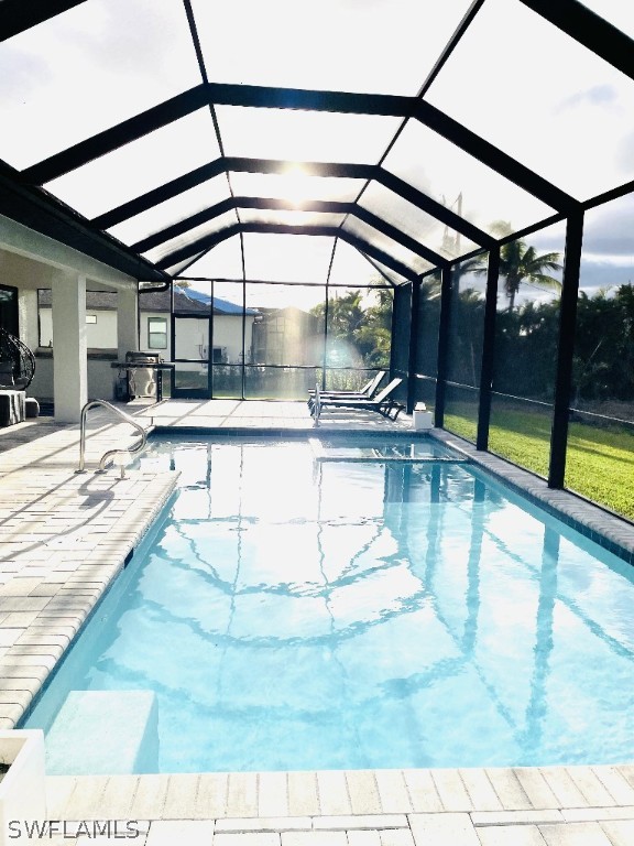 view of pool with glass enclosure and a patio area