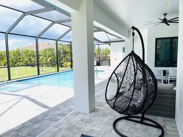 view of pool featuring a patio, glass enclosure, and ceiling fan