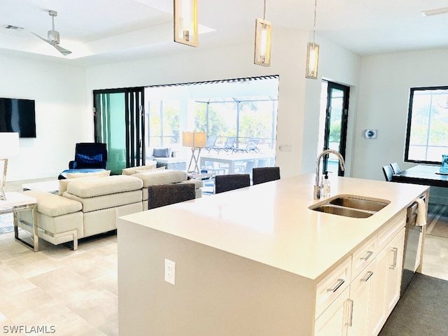 kitchen with ceiling fan, sink, hanging light fixtures, an island with sink, and white cabinets