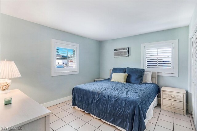 bedroom with a wall mounted air conditioner, light tile flooring, and multiple windows