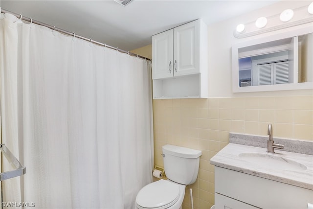 bathroom with large vanity, tasteful backsplash, toilet, and tile walls