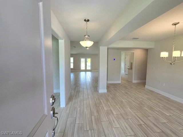 interior space with an inviting chandelier, visible vents, baseboards, and wood finish floors