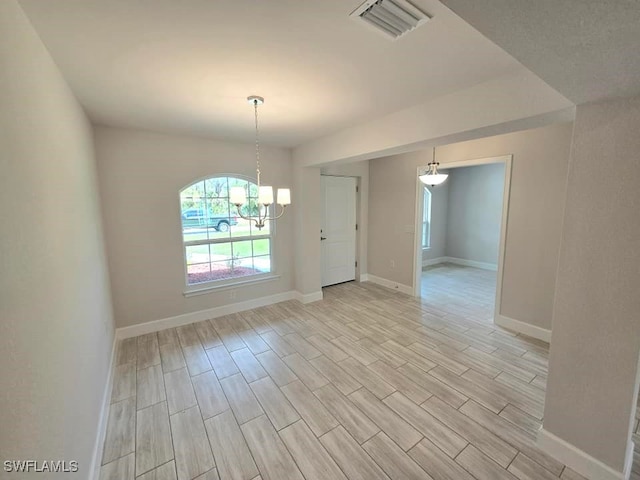 unfurnished room featuring a notable chandelier, baseboards, visible vents, and wood finish floors