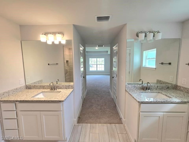 bathroom with visible vents, two vanities, baseboards, and a sink