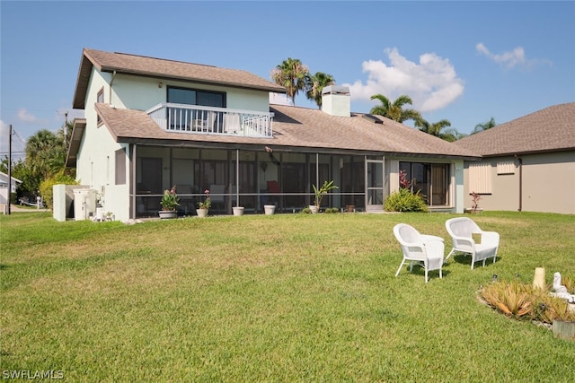 rear view of property with a balcony, a sunroom, and a lawn