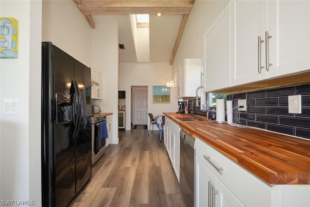 kitchen with wooden counters, light wood-type flooring, white cabinets, stainless steel appliances, and beamed ceiling