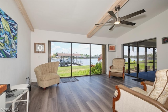 sitting room with dark wood-type flooring, a water view, lofted ceiling with beams, and ceiling fan