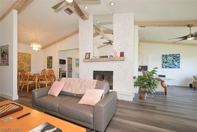 living room with a fireplace, dark hardwood / wood-style flooring, beamed ceiling, and ceiling fan with notable chandelier