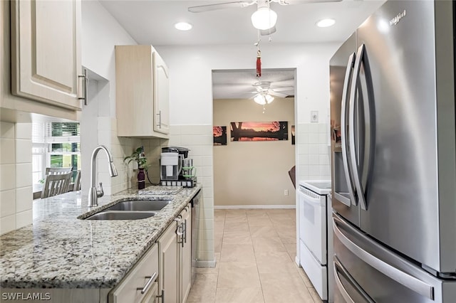 kitchen with ceiling fan, tasteful backsplash, stainless steel refrigerator with ice dispenser, light stone counters, and sink