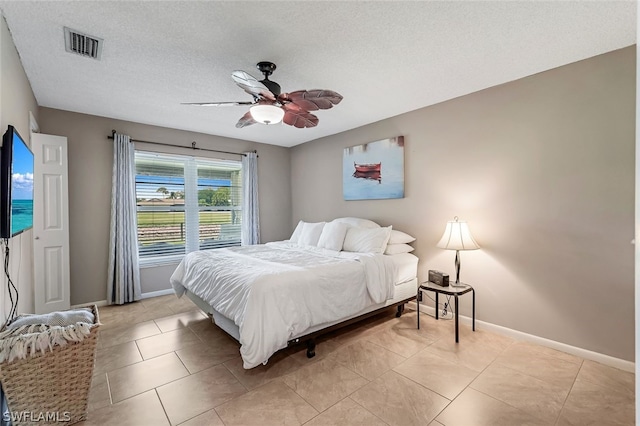 tiled bedroom with ceiling fan and a textured ceiling