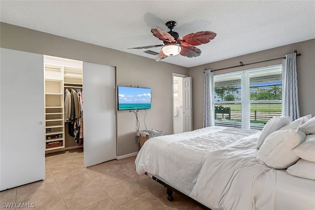 tiled bedroom featuring a spacious closet, a textured ceiling, a closet, and ceiling fan