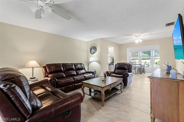 living room with a textured ceiling, ceiling fan, and light tile floors