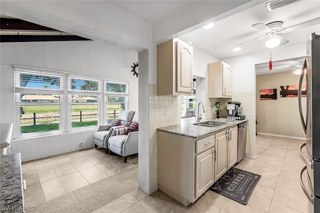 kitchen with light stone countertops, ceiling fan, sink, and light tile floors