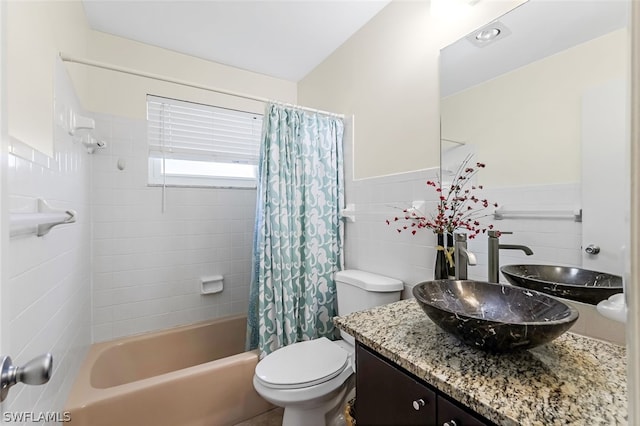 full bathroom with tile walls, shower / bath combination with curtain, vanity, and toilet