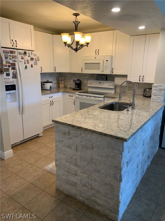 kitchen featuring pendant lighting, sink, white appliances, light tile patterned floors, and white cabinetry