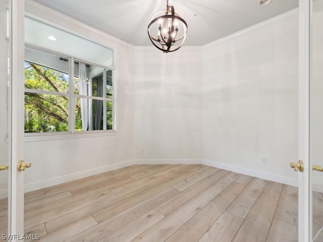 spare room featuring light hardwood / wood-style floors, crown molding, and a notable chandelier