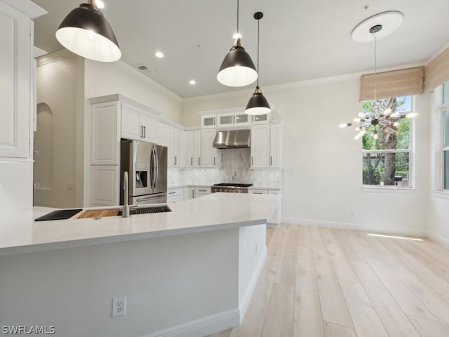 kitchen featuring wall chimney exhaust hood, white cabinetry, stainless steel refrigerator with ice dispenser, and hanging light fixtures