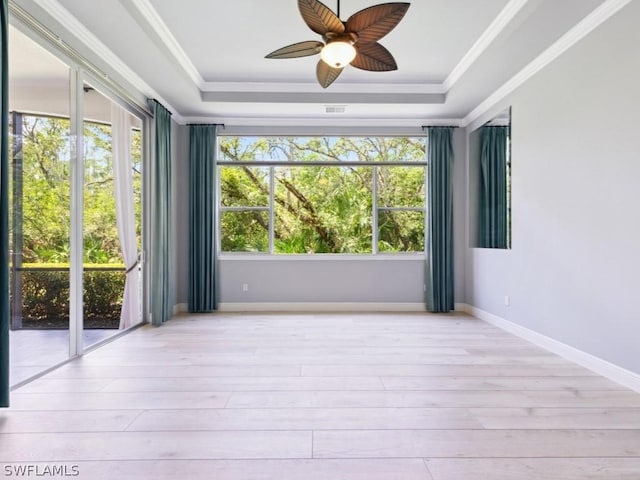 unfurnished room with a tray ceiling, ceiling fan, crown molding, and light hardwood / wood-style floors