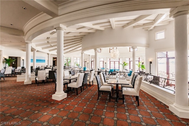 interior space with ornate columns, beam ceiling, a high ceiling, carpet, and a chandelier