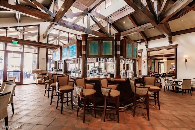 bar with high vaulted ceiling, plenty of natural light, ceiling fan, and tile floors