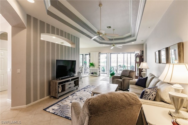 living room with ceiling fan, a raised ceiling, ornamental molding, and light tile floors