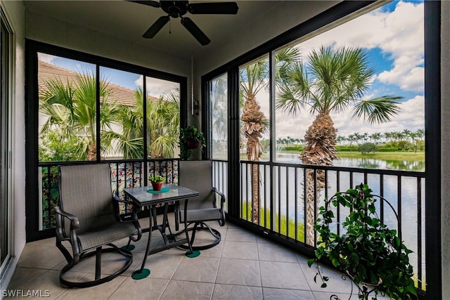 sunroom / solarium with ceiling fan and a water view