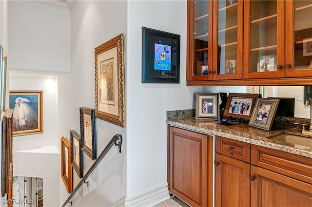 interior space featuring light stone counters, sink, crown molding, and light wood-type flooring