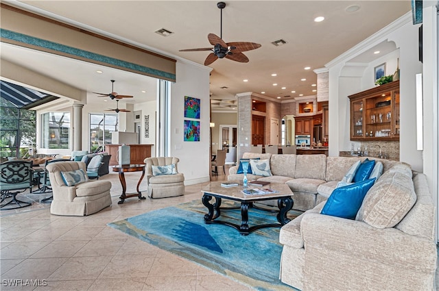 living room with decorative columns, crown molding, and light tile patterned floors