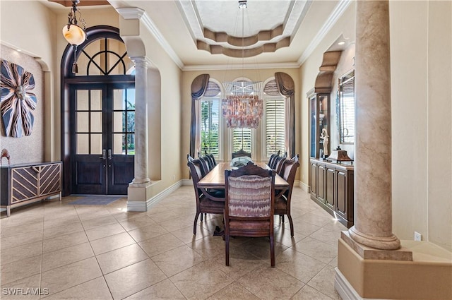 tiled dining area with decorative columns, crown molding, a raised ceiling, and a notable chandelier