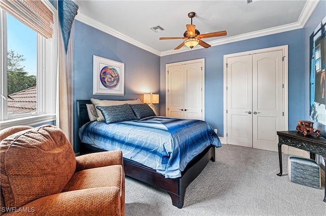 carpeted bedroom with ceiling fan, ornamental molding, and multiple closets