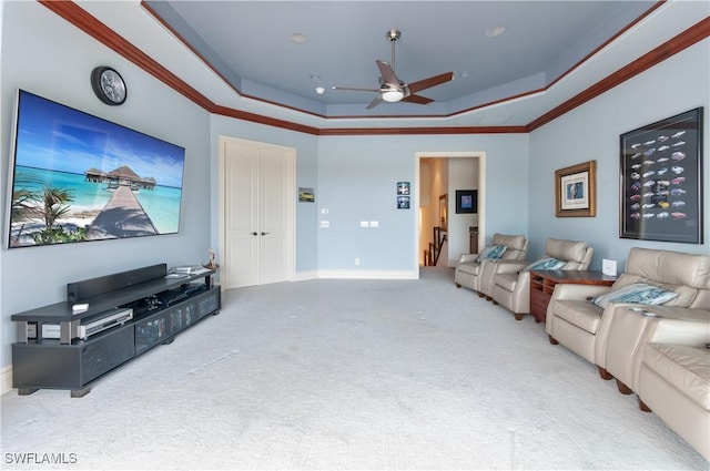 carpeted living room featuring a tray ceiling, ornamental molding, and ceiling fan