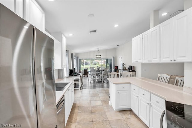 kitchen with vaulted ceiling, white cabinetry, appliances with stainless steel finishes, and kitchen peninsula