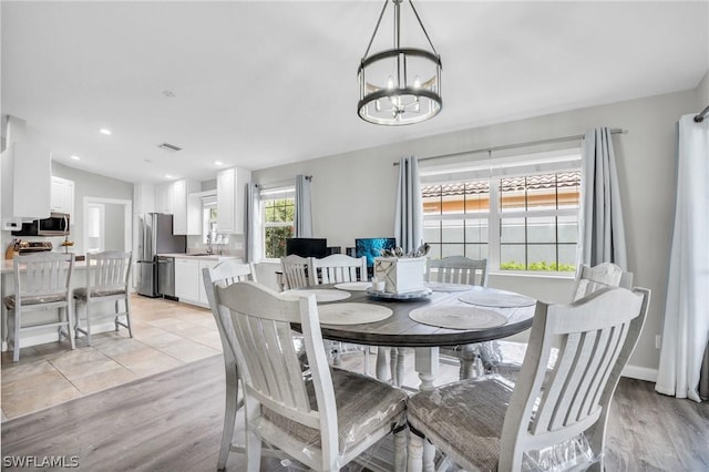 dining space featuring sink, a chandelier, vaulted ceiling, and light hardwood / wood-style flooring