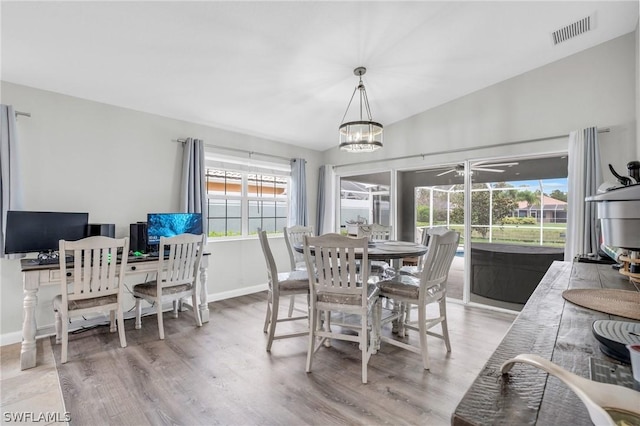 dining room featuring vaulted ceiling, ceiling fan with notable chandelier, and hardwood / wood-style floors