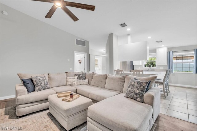 tiled living room featuring ceiling fan and high vaulted ceiling