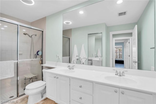 bathroom featuring vanity, toilet, and a shower with door