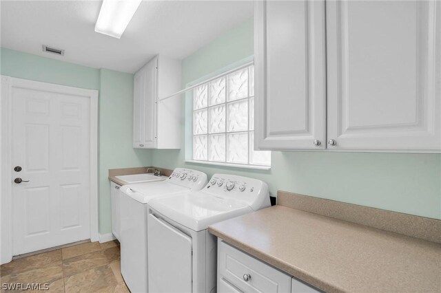 clothes washing area with sink, cabinets, and washing machine and clothes dryer