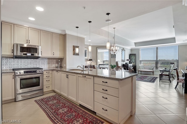 kitchen featuring pendant lighting, kitchen peninsula, sink, a tray ceiling, and appliances with stainless steel finishes