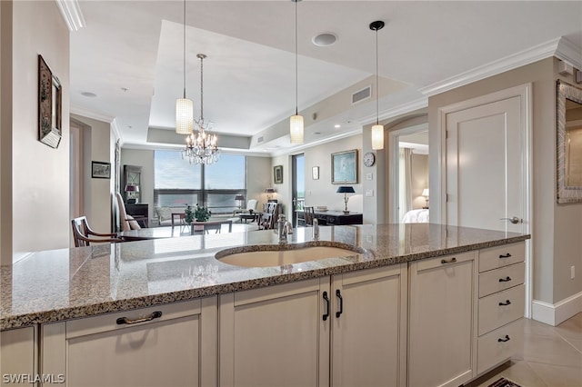 kitchen featuring a raised ceiling, light stone counters, and sink