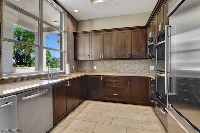 kitchen with decorative backsplash, sink, light stone counters, and stainless steel appliances