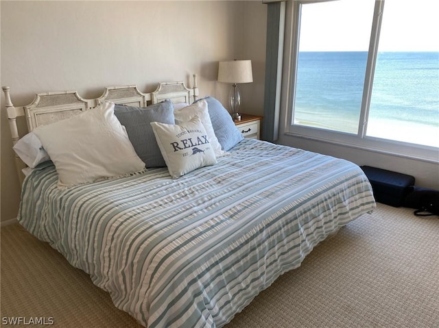 bedroom with a water view and light colored carpet