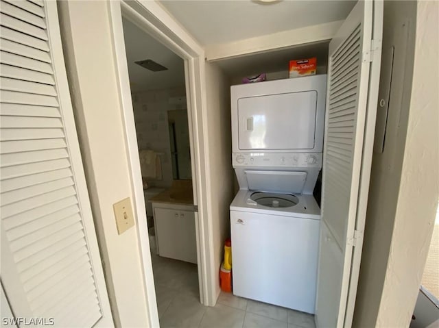 clothes washing area with light tile patterned floors and stacked washing maching and dryer