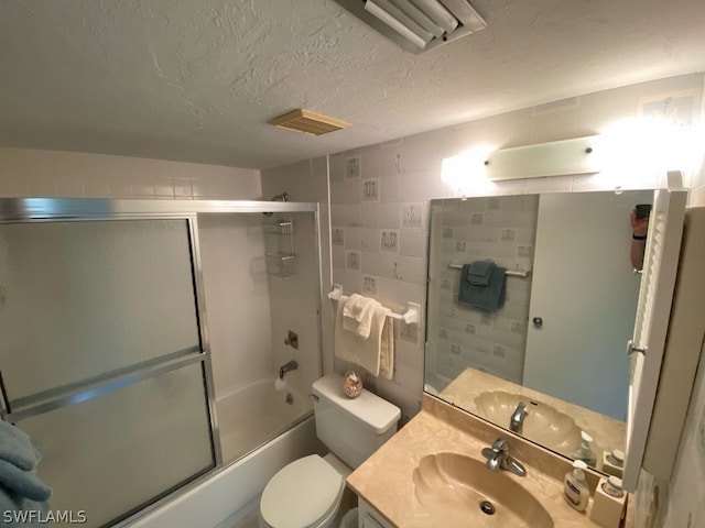 full bathroom with toilet, combined bath / shower with glass door, a textured ceiling, and vanity